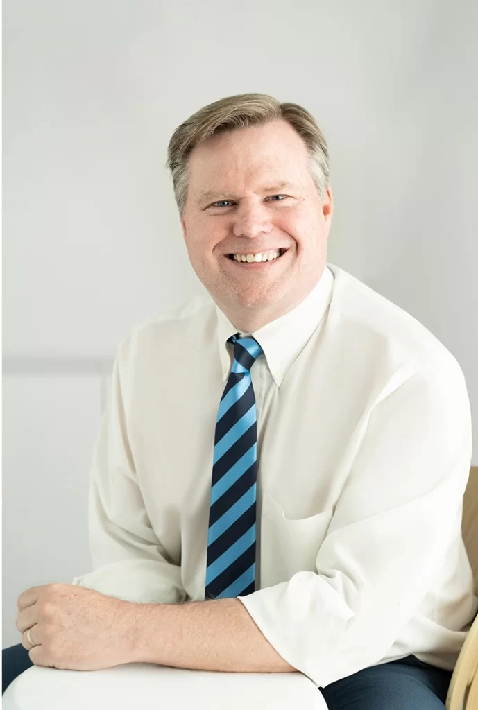 man-in-white-button-up-with-striped-tie-smiling-for-the-camera