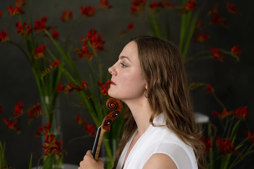 brunette-profile-with-violin-under-shin-and-red-flowers-in-the-nackground