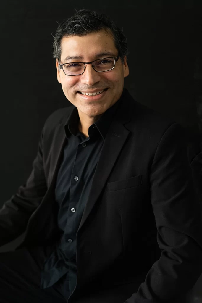 man-with-glasses-wearing-black-business-attire-smiling