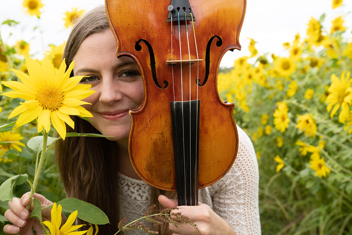 woman-holding-violin-in-yellow-flower-field