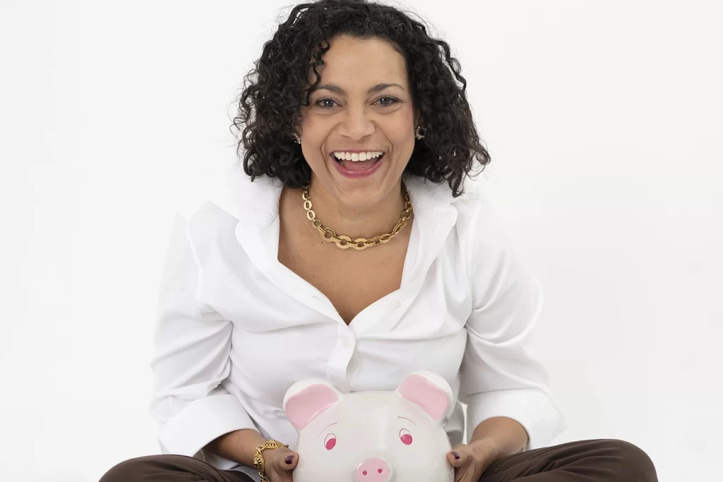 woman-sitting-on-the-floor-holding-piggy-bank-smiling