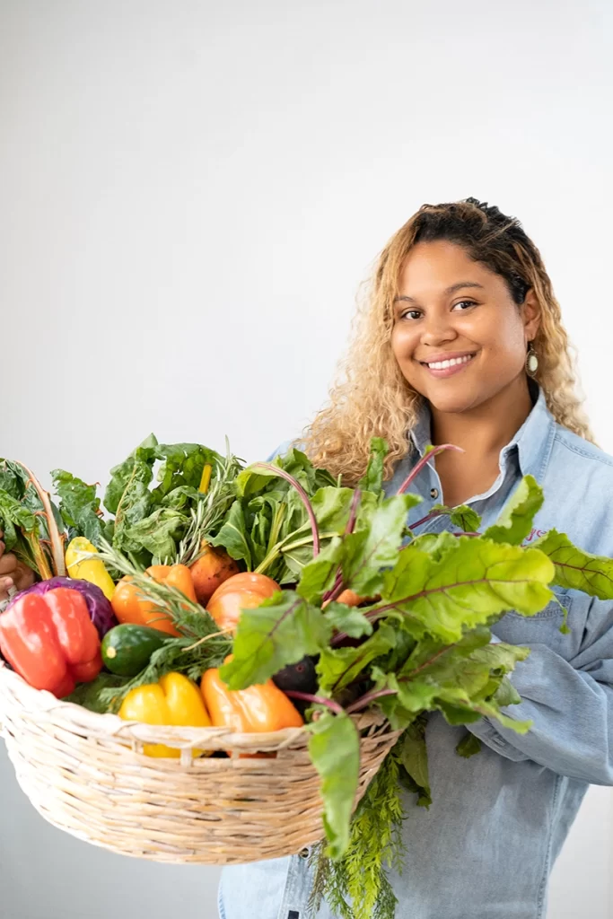 woman-smiling-and-holding-basket-full-of-fresh-produce