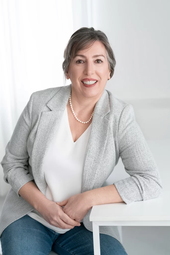 woman-smiling-while-posing-in-business-casual-attire-at-table