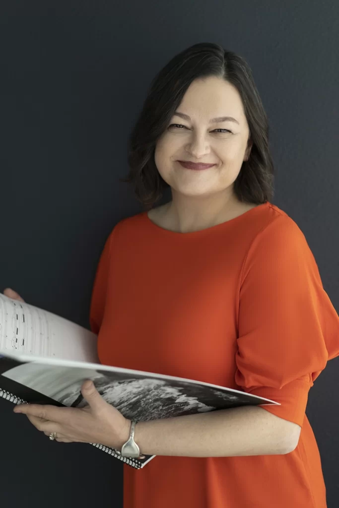 composer-in-orange-shirt-smiling-while-holding-sheet-music