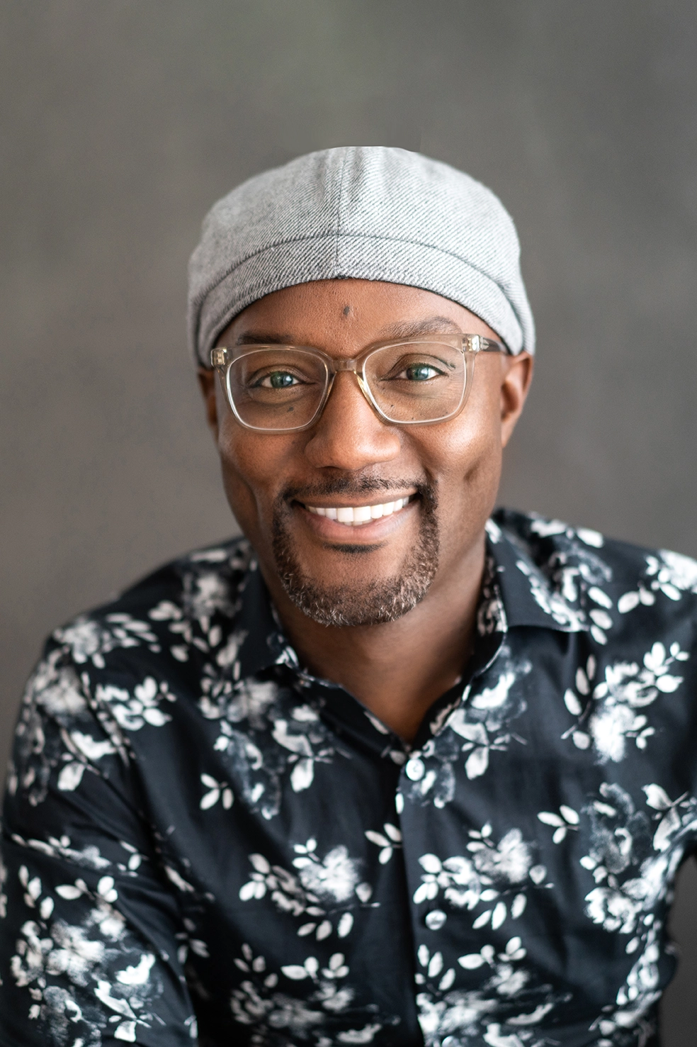 Man-with-glasses-and-hat-in-floral-button-up-shirt-smiling